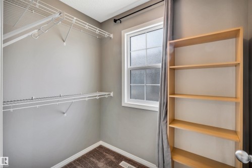 Room featuring a double-hung window, wire shelving system and wall-to-wall carpeting - 571 Orchards Boulevard Sw, Edmonton, AB - Indoor With Storage