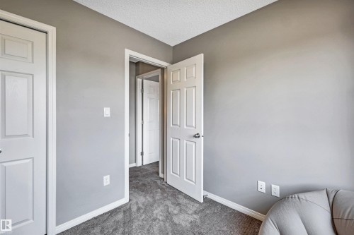 Interior room featuring neutral gray wall paint, white trim, and textured gray carpeting - 571 Orchards Boulevard Sw, Edmonton, AB - Indoor