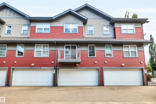 Townhome exterior featuring horizontal red siding and gray shingle accents - 571 Orchards Boulevard Sw, Edmonton, AB - Outdoor With Facade