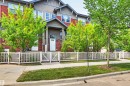 Multi-level townhome featuring a red and gray facade, a covered entry porch, and white paneled door - 571 Orchards Boulevard Sw, Edmonton, AB  - Outdoor 
