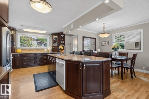 Kitchen featuring dark wood cabinetry, light wood-finish flooring, and a central island with a light-toned countertop - 27 Milford Crescent, Sherwood Park, AB - Indoor Photo Showing Other Room