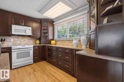 Kitchen featuring rich wood cabinetry, light-toned countertops, a full suite of white appliances, and a tiled backsplash - 27 Milford Crescent, Sherwood Park, AB - Indoor Photo Showing Kitchen