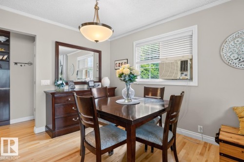 Dining area with light wood-finish flooring, crown molding, and a polished brass and frosted glass ceiling fixture - 27 Milford Crescent, Sherwood Park, AB - Indoor Photo Showing Dining Room