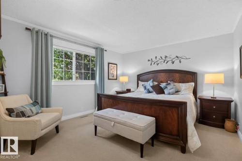 Bright bedroom featuring a large window, plush carpet flooring, crown molding, and a neutral wall color - 27 Milford Crescent, Sherwood Park, AB - Indoor Photo Showing Bedroom