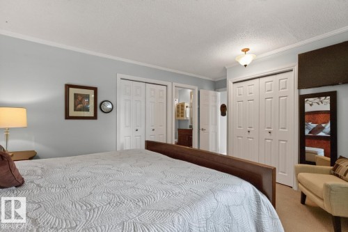 Spacious sleeping area featuring light blue walls, white bi-fold closet doors, and crown molding - 27 Milford Crescent, Sherwood Park, AB - Indoor Photo Showing Bedroom
