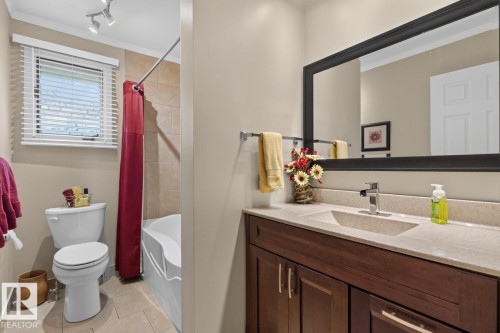 Dual-zone bathroom featuring a wood-finish vanity with dual sinks, quartz countertop, and contemporary matte black framed mirror - 27 Milford Crescent, Sherwood Park, AB - Indoor Photo Showing Bathroom