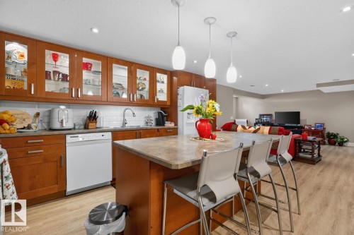 Kitchen island with integrated breakfast bar seating, featuring a stone-finish countertop - 27 Milford Crescent, Sherwood Park, AB - Indoor