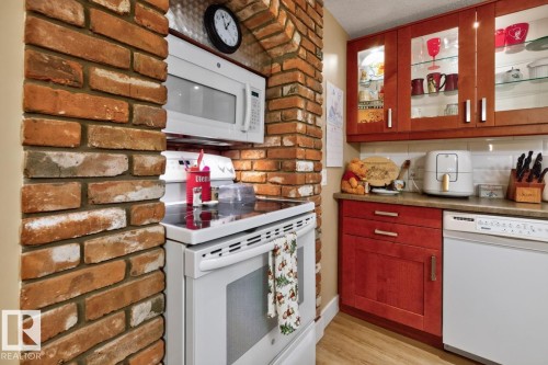 Brick archway with an integrated microwave oven and a sleek electric range - 27 Milford Crescent, Sherwood Park, AB - Indoor Photo Showing Kitchen