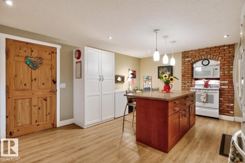 Kitchen featuring a large central island with a stone countertop and wood-finish cabinetry - 27 Milford Crescent, Sherwood Park, AB - Indoor Photo Showing Kitchen