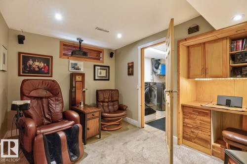 Dedicated media room featuring built-in wood cabinetry with shelving, recessed ceiling lighting, and plush leather seating with integrated footrests - 27 Milford Crescent, Sherwood Park, AB - Indoor