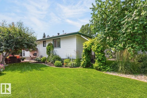 Expansive green lawn with mature trees and a vine-covered archway - 27 Milford Crescent, Sherwood Park, AB - Outdoor