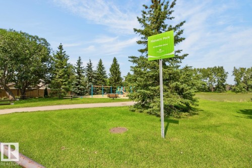 Expansive manicured lawn with mature shade trees and a paved pathway, complemented by nearby playground equipment and open green space ideal for outdoor recreation - 27 Milford Crescent, Sherwood Park, AB - Outdoor With View