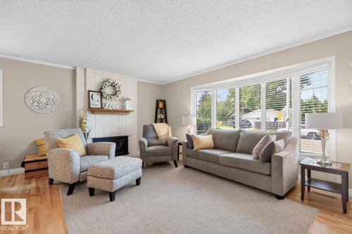 Bright, light-filled living room showcasing hardwood flooring, a neutral color palette, and expansive multi-pane windows with exterior shutters - 27 Milford Crescent, Sherwood Park, AB - Indoor Photo Showing Living Room