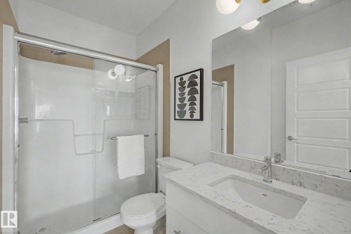 Contemporary bathroom featuring a white vanity with an integrated sink and light-colored countertop - #435 1008 Rosenthal Bv Nw, Edmonton, AB - Indoor Photo Showing Bathroom