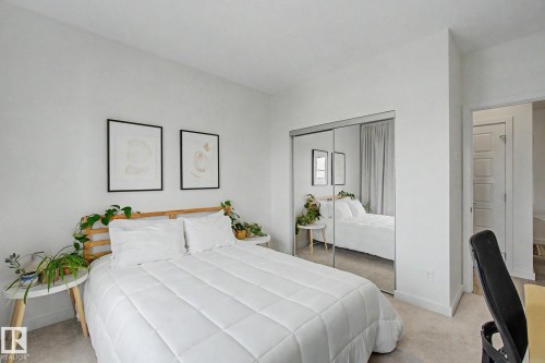 Bedroom featuring light-colored carpet, white walls, and a mirrored sliding closet door - #435 1008 Rosenthal Bv Nw, Edmonton, AB - Indoor Photo Showing Bedroom