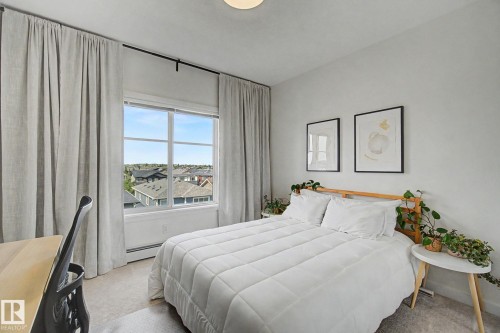 Window with a multi-pane design, neutral wall color, light-colored carpeting, white baseboards, and a ceiling-mounted light fixture - #435 1008 Rosenthal Bv Nw, Edmonton, AB - Indoor Photo Showing Bedroom