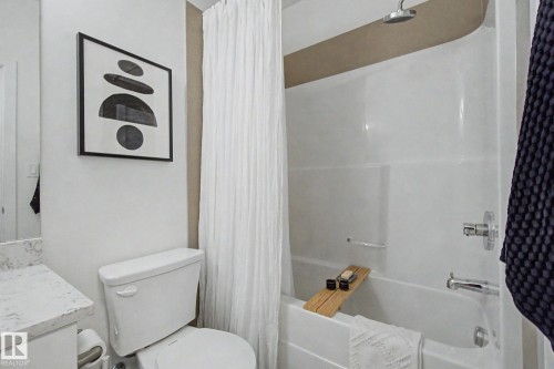Full white bathtub and shower combination with chrome fixtures - #435 1008 Rosenthal Bv Nw, Edmonton, AB - Indoor Photo Showing Bathroom