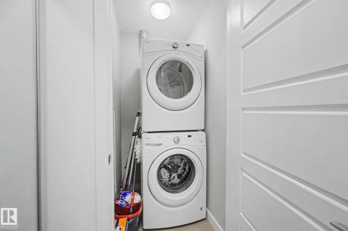 Dedicated laundry closet featuring a stacked washer and dryer, recessed overhead lighting, and modern white paneled doors - #435 1008 Rosenthal Bv Nw, Edmonton, AB - Indoor Photo Showing Laundry Room