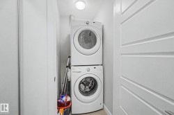 Dedicated laundry closet featuring a stacked washer and dryer, recessed overhead lighting, and modern white paneled doors - 