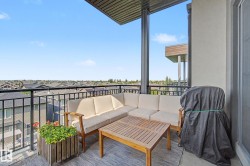 Spacious covered balcony featuring a black metal railing, concrete flooring, and an exterior door - 