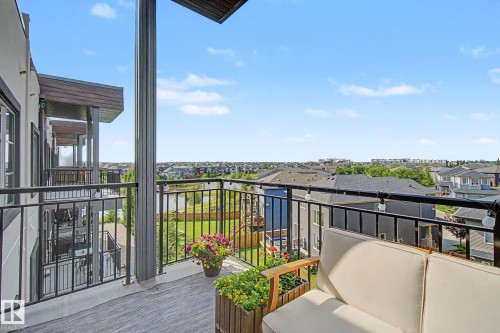 Private balcony featuring composite decking, black metal railings, and string lighting - #435 1008 Rosenthal Bv Nw, Edmonton, AB - Outdoor With Exterior