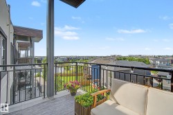 Private balcony featuring composite decking, black metal railings, and string lighting - 