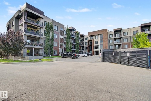 Contemporary multi-story building featuring a facade with mixed materials including brick, stucco, and wood-finish accents - #435 1008 Rosenthal Bv Nw, Edmonton, AB - Outdoor With Balcony With Facade