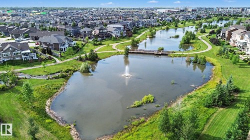 Expansive green spaces featuring multiple ponds with water features, winding pathways, and a pedestrian bridge - #435 1008 Rosenthal Bv Nw, Edmonton, AB - Outdoor With Body Of Water With View