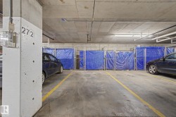 Designated parking space within a concrete subterranean garage, featuring overhead pipework and fluorescent lighting - 