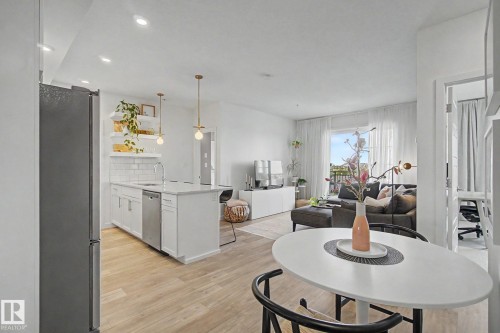 Open-concept living area featuring wood-finish flooring, recessed lighting, and a kitchen island with a built-in sink and dishwasher - #435 1008 Rosenthal Bv Nw, Edmonton, AB - Indoor