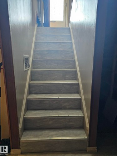 Staircase featuring light gray patterned treads with metal edge trim, white risers, and white-painted stringers - 13103 63 Street Nw, Edmonton, AB - Indoor Photo Showing Other Room