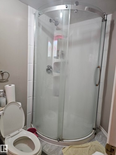 Curved glass shower enclosure with chrome hardware and integrated shelving - 13103 63 Street Nw, Edmonton, AB - Indoor Photo Showing Bathroom