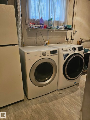 Laundry area featuring wood-finish flooring, a window with sheer curtains, and a wire wall shelf - 13103 63 Street Nw, Edmonton, AB - Indoor Photo Showing Laundry Room