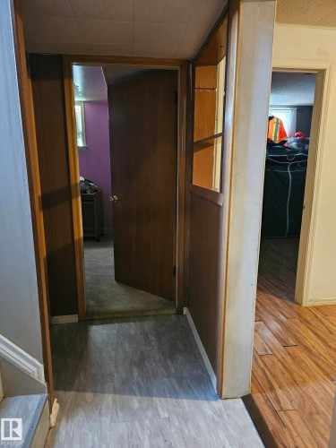 Hallway featuring wood-finish flooring, a built-in shelving unit with wood paneling, and interior wood doors - 13103 63 Street Nw, Edmonton, AB - Indoor Photo Showing Other Room