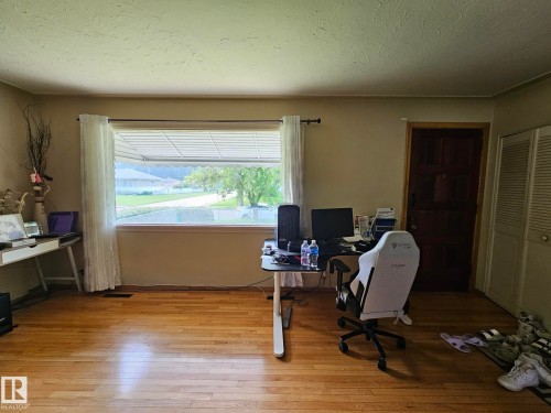 Hardwood flooring throughout a room featuring a large picture window with venetian blinds, a paneled interior door, and bi-fold closet doors - 13103 63 Street Nw, Edmonton, AB - Indoor Photo Showing Office