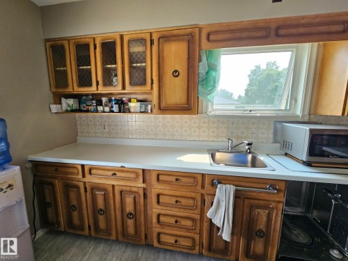 Kitchen featuring wood cabinetry, a stainless steel sink, and light-toned countertops - 13103 63 Street Nw, Edmonton, AB - Indoor Photo Showing Kitchen