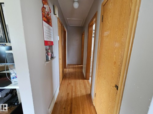 Hallway featuring wood-finish flooring, light-colored walls, and multiple wood-grain doors - 13103 63 Street Nw, Edmonton, AB - Indoor Photo Showing Other Room