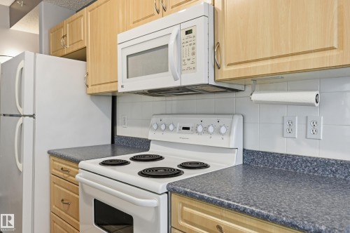 Full kitchen with light wood-finish cabinetry, white tile backsplash, and speckled countertops - #203 11103 84 Av Nw, Edmonton, AB - Indoor Photo Showing Kitchen