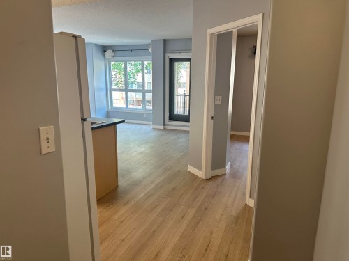 Open-concept living area featuring wood-finish flooring, light gray walls, and white trim - #203 11103 84 Av Nw, Edmonton, AB - Indoor Photo Showing Other Room