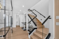 Modern staircase featuring glass panel railings and matte black handrails - 