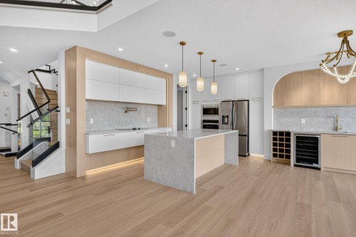 Contemporary kitchen featuring a waterfall island with pendant lighting, integrated appliances, and a built-in wine cooler - 8791 Mayday Ln Sw Sw, Edmonton, AB - Indoor Photo Showing Kitchen With Upgraded Kitchen