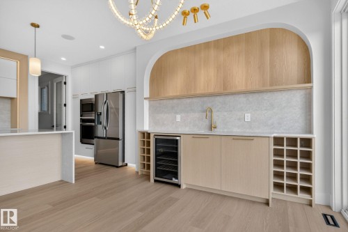 Contemporary kitchen featuring light wood-finish flooring, white cabinetry, and stainless steel appliances - 8791 Mayday Ln Sw Sw, Edmonton, AB - Indoor Photo Showing Kitchen With Upgraded Kitchen