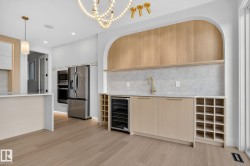Contemporary kitchen featuring light wood-finish flooring, white cabinetry, and stainless steel appliances - 