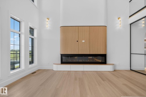 Great room featuring a built-in media center with wood-finish cabinetry, an electric linear fireplace, and integrated lower storage - 8791 Mayday Ln Sw Sw, Edmonton, AB - Indoor With Fireplace