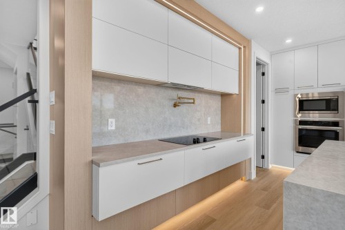 Modern kitchen featuring integrated appliances, light wood-finish cabinetry, and a full-height backsplash - 8791 Mayday Ln Sw Sw, Edmonton, AB - Indoor Photo Showing Kitchen With Upgraded Kitchen