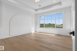 Bright room with wide plank wood-finish flooring, a tray ceiling, and recessed lighting - 