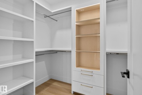 Custom closet system featuring extensive shelving, hanging rods, and built-in drawers with brass hardware - 8791 Mayday Ln Sw Sw, Edmonton, AB - Indoor With Storage