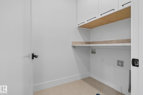 Dedicated utility space featuring light-toned flooring, crisp white walls, and built-in cabinetry with matte black hardware - 8791 Mayday Ln Sw Sw, Edmonton, AB - Indoor