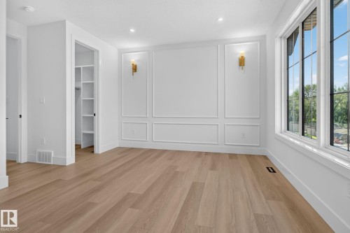 Spacious room featuring wood-finish flooring, large windows, and decorative wall molding - 8791 Mayday Ln Sw Sw, Edmonton, AB - Indoor Photo Showing Other Room