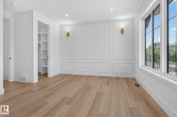 Spacious room featuring wood-finish flooring, large windows, and decorative wall molding - 